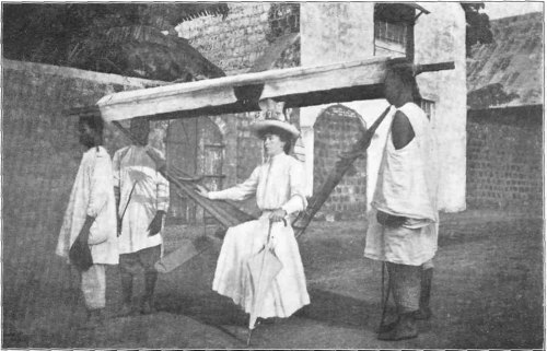 Mrs. Davis in a Borrowed "Hammock," the Local Means of Transport on the West Coast.