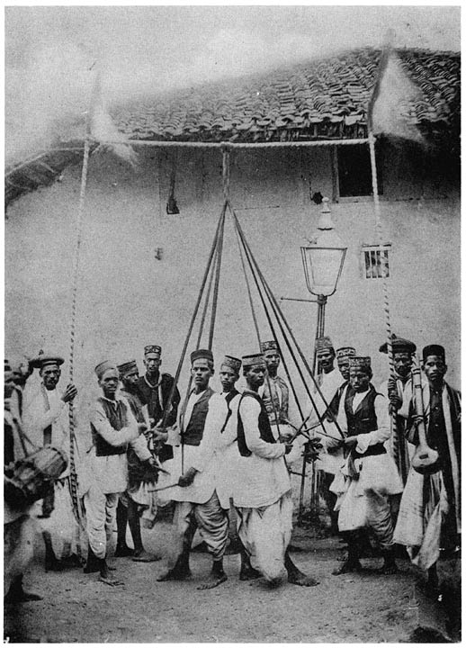 Koshti men dancing a figure, holding strings and beating sticks