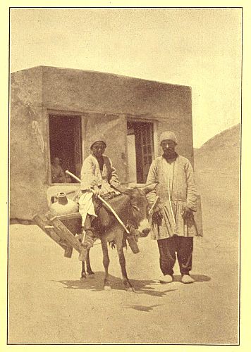photograph of boy on donkey and man standing by