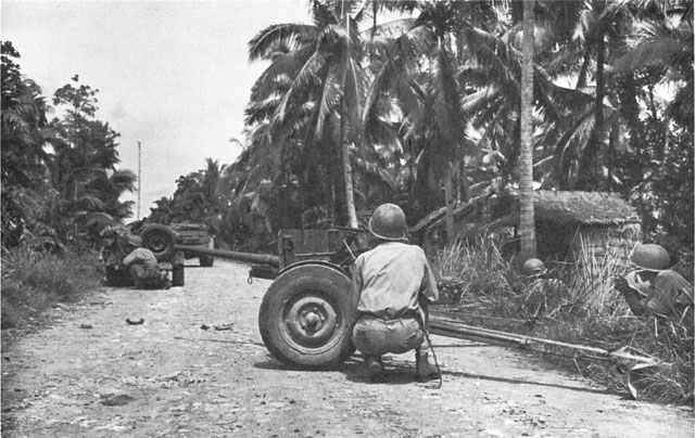 U.S. ANTITANK PLATOON under enemy fire at Jaro. Soldier in foreground is taking cover behind a 37-mm. antitank gun M3.