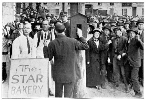 A huge crowd looks on as a man pulls an alarm.